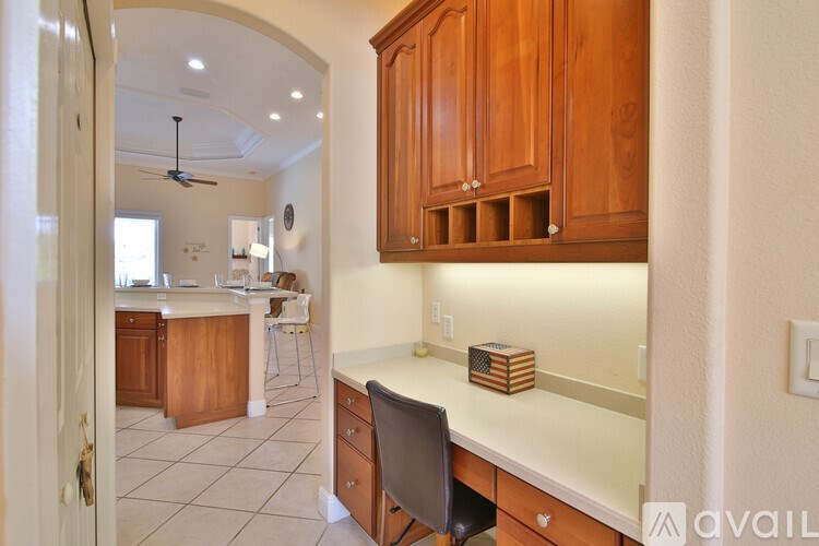 A kitchen with wooden cabinets and a counter with a chair.