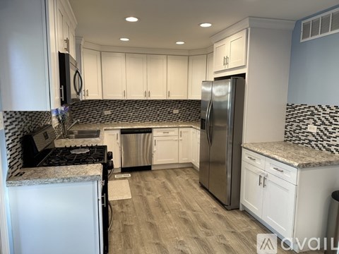 A kitchen with white cabinets and a black and white tiled backsplash.