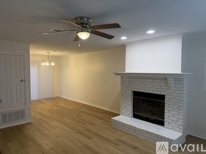 A living room with a fireplace and a ceiling fan.
