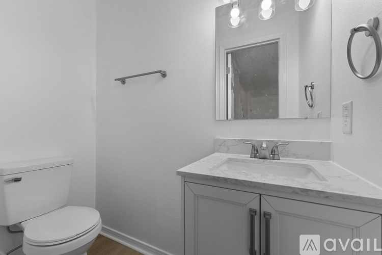 A bathroom with a toilet, sink, and mirror.