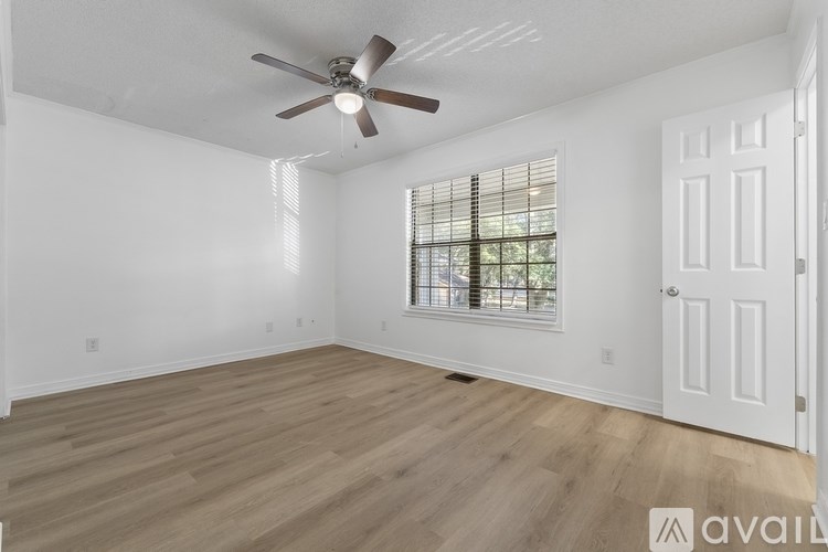 A room with a ceiling fan and a window with blinds.