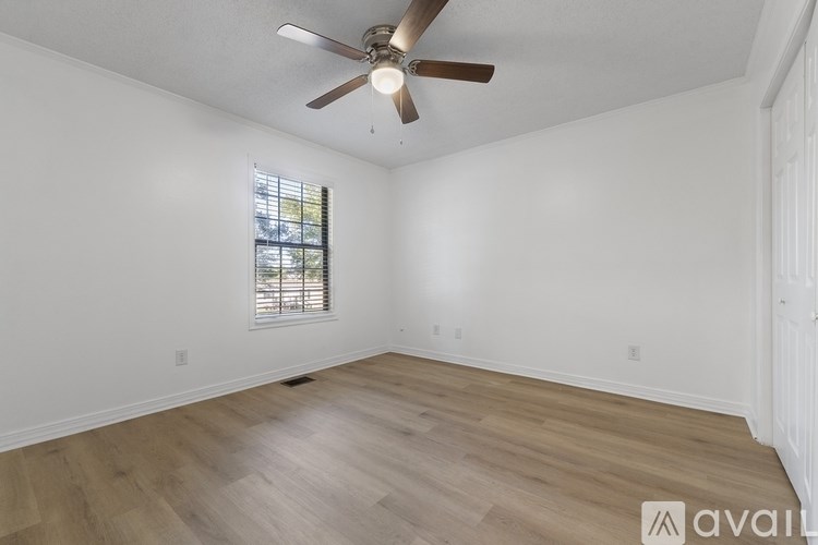 A room with a ceiling fan and wooden flooring.