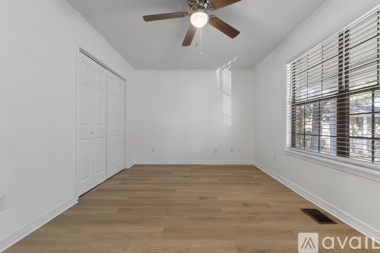 A room with a ceiling fan and a window with blinds.