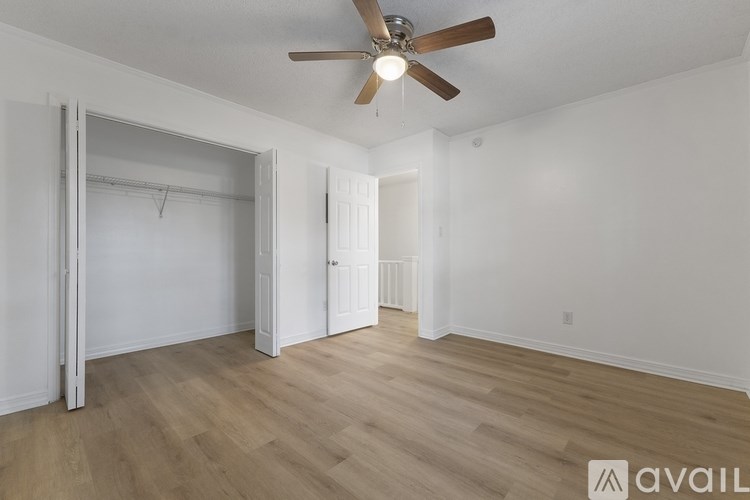 A room with a ceiling fan and wooden flooring.