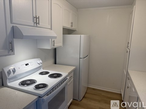 A kitchen with a white stove top oven and a white refrigerator.