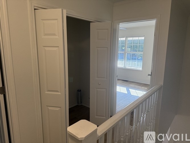 A white door is open to a bathroom with a toilet and a window.