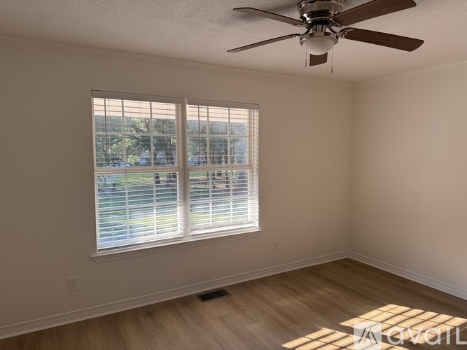 A room with a ceiling fan and a window with blinds.
