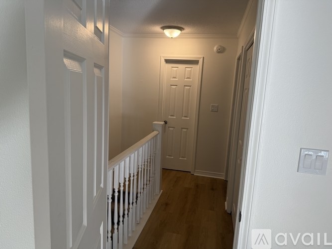 A hallway with white walls and a wooden floor.