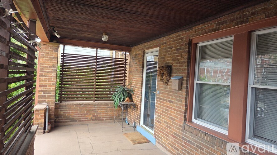 A patio with a wooden bench and a potted plant.