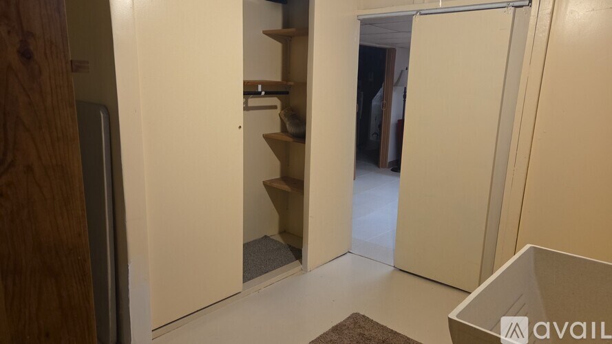 A room with a brown rug and a white cabinet with a shelf.