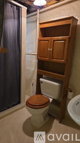 A toilet in a small bathroom with a wooden cabinet above it.