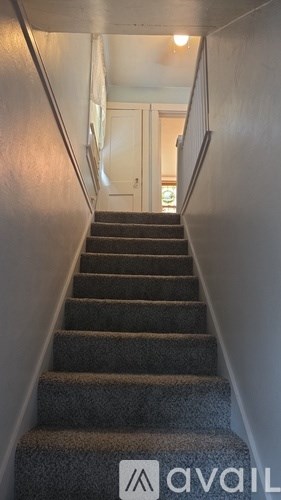 A staircase with a metal railing and a textured carpet.