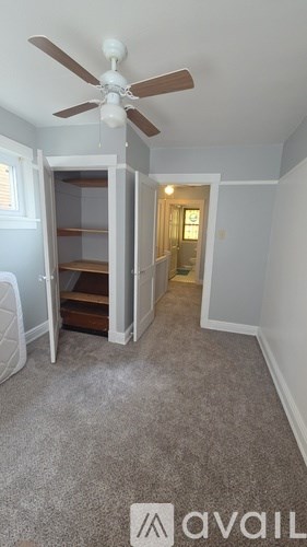 A room with a carpeted floor and a ceiling fan.