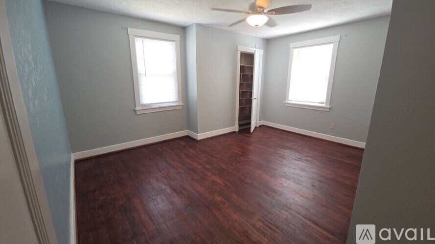 A room with wooden floors and two windows.