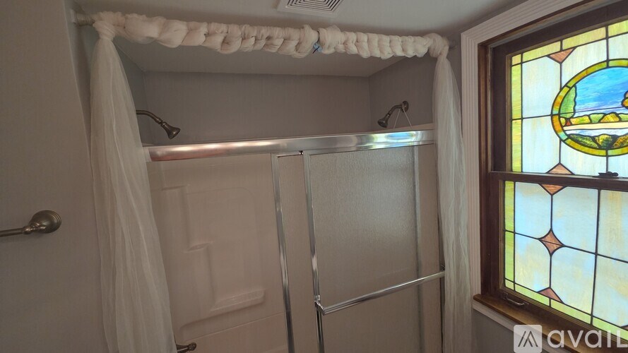 A bathroom with a shower curtain and a stained glass window.