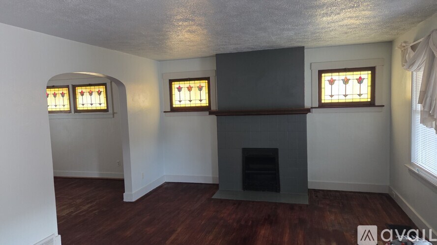 A room with a fireplace and three windows.