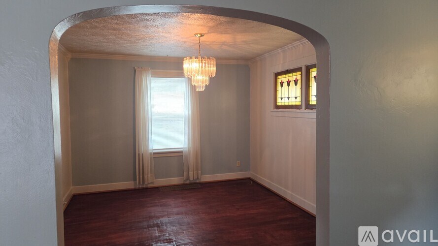A room with a chandelier, a window with curtains, and a stained glass window on the wall.