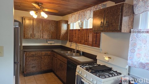 A kitchen with wooden cabinets and a white stove top oven.