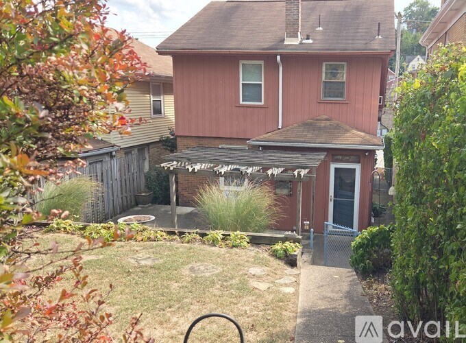 A red house with a porch and a fence in front of it.