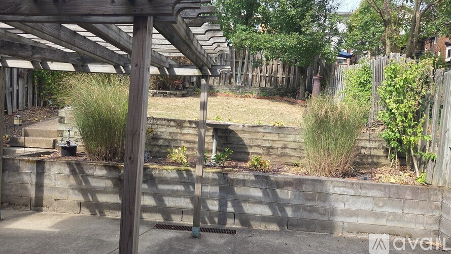 A patio area with a wooden pergola and a stone wall.