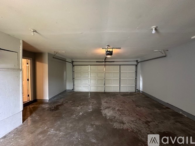 A spacious garage with a concrete floor and a white door.