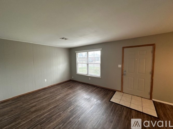 A room with wooden flooring and a door is available for rent.