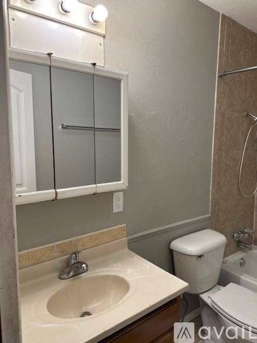 A bathroom with a sink, toilet, and mirror.