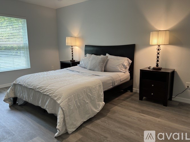 A bedroom with a large bed and two lamps on either side.