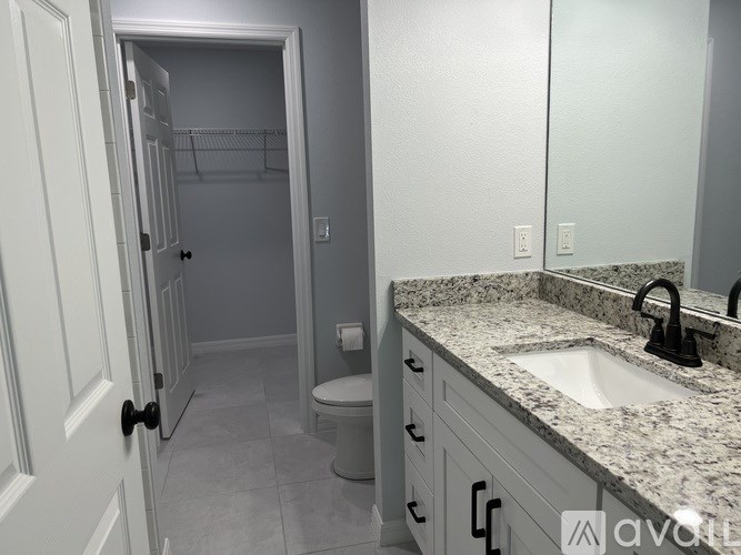 A bathroom with a sink, toilet and a mirror.