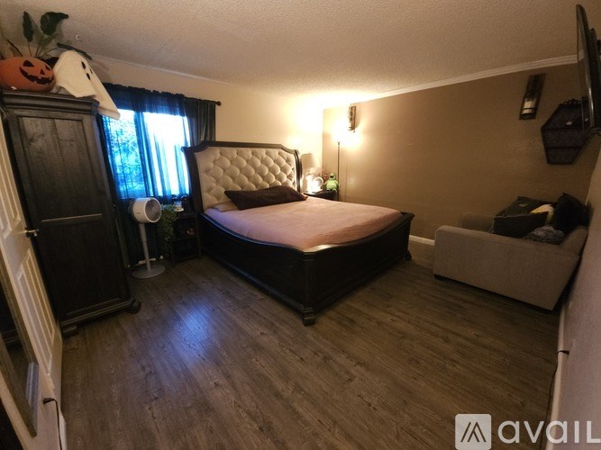 A bedroom with a bed, a chair, and a cabinet.