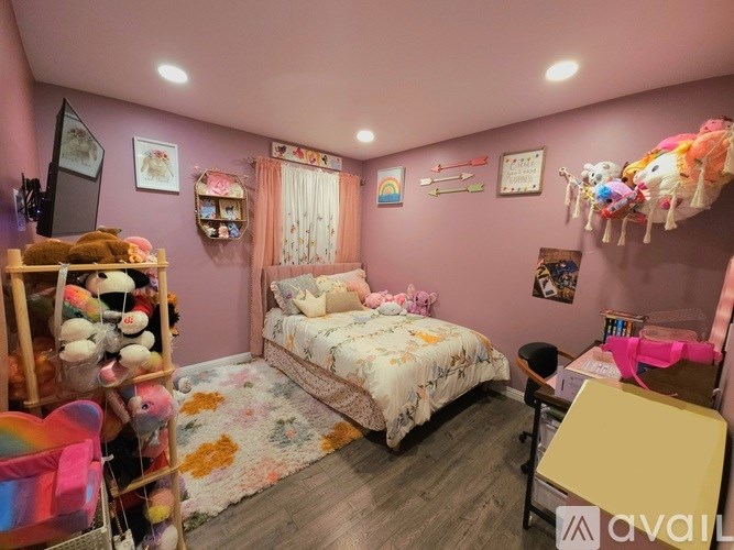 A child's bedroom with a bed, desk, and toy shelves.