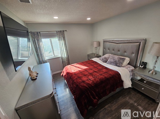 A bedroom with a bed, nightstand, and window.