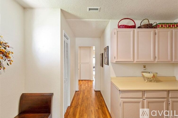 A kitchen with white cabinets and a wooden floor.