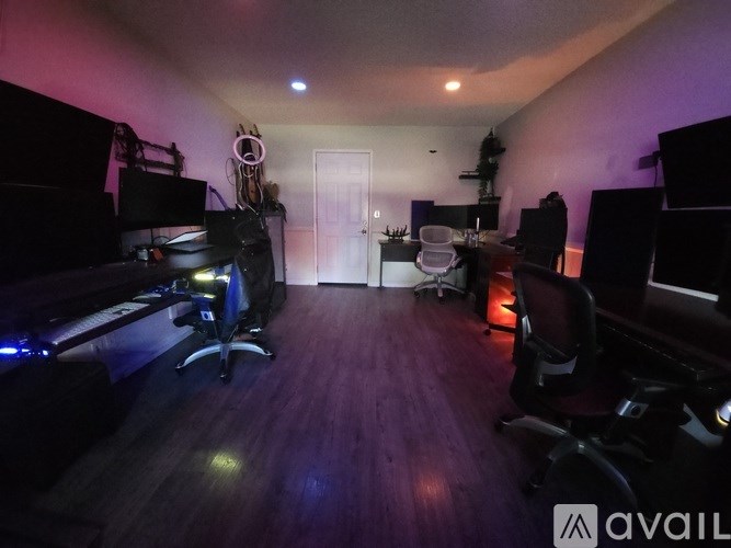 A room with a desk, chairs, and a computer setup.