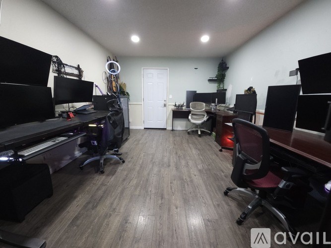 A room with a desk, chairs, and computer setups.