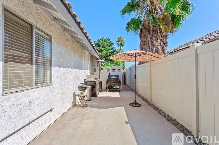 A patio with a white wall, a palm tree, and a white fence.