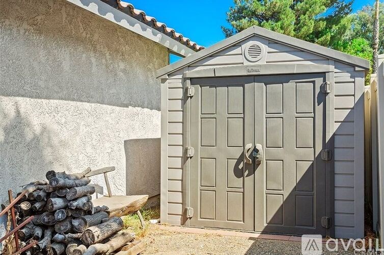 A grey garage door with a black handle and a stack of logs to the left.