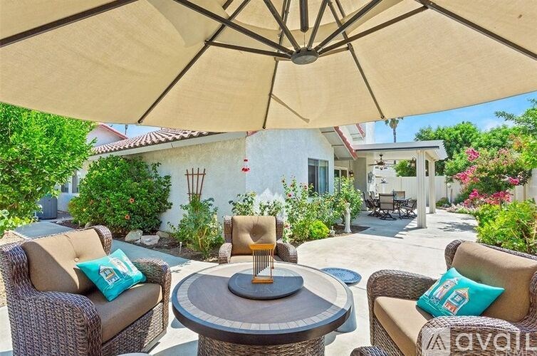 A patio with a table and chairs under an umbrella.
