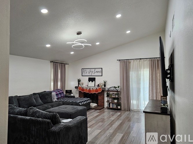 A living room with a fireplace and a TV on the wall.