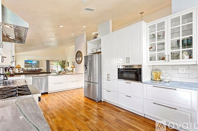 A modern kitchen with white cabinets and stainless steel appliances.