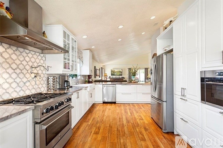 A kitchen with white cabinets and a wooden floor.