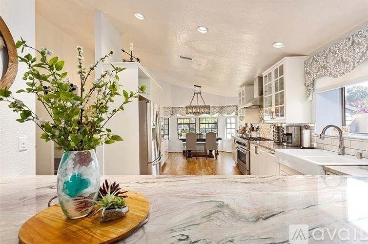 A kitchen with a marble countertop and a wooden tray holding a vase and succulents.
