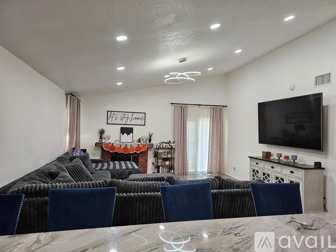 A living room with a grey couch and a television on the wall.