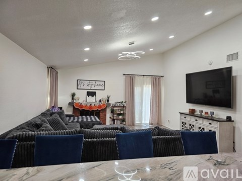 A living room with a grey couch and a television on the wall.