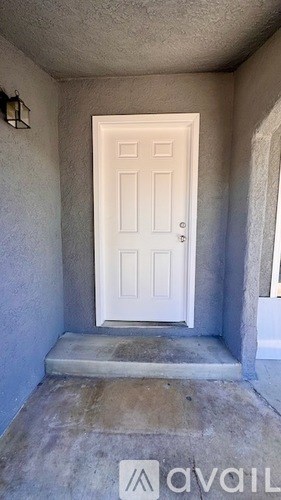 A white door is in a hallway with a stone floor.