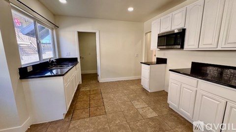 A kitchen with white cabinets and black countertops.