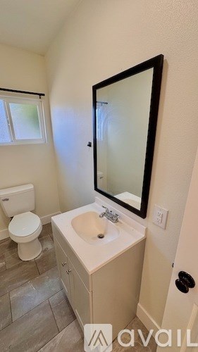 A bathroom with a toilet, sink, and mirror.