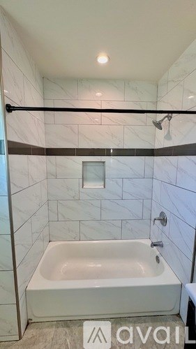 A white bathtub in a bathroom with marble tiles.