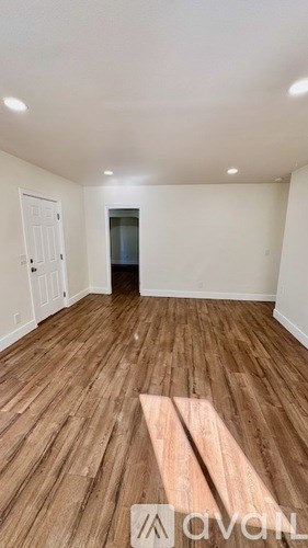 A room with wooden flooring and white walls.
