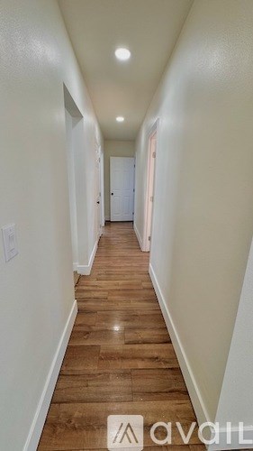 A long hallway with wood floors and white walls.